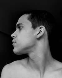 Close-up portrait of shirtless man against black background