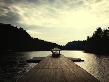 Pier on lake against cloudy sky