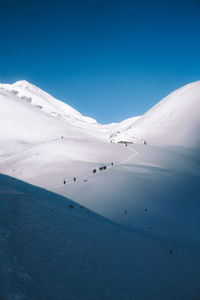 Scenic view of snowcapped mountains against clear blue sky