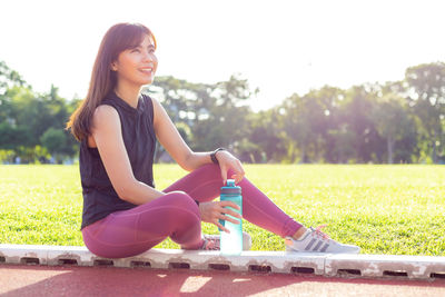 Young woman sitting on field against plants