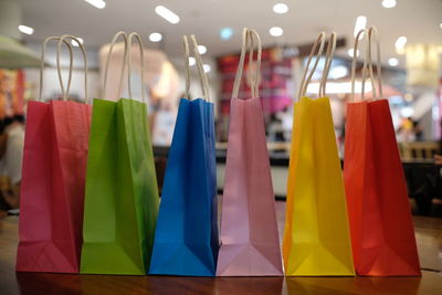 Close-up of colorful shopping bags in row on wooden table