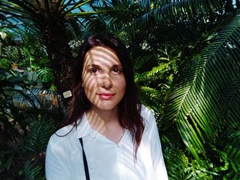 Portrait of young woman standing against trees