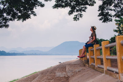 Man by tree on mountain against sky