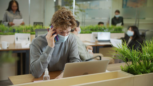 Woman using mobile phone while sitting on table