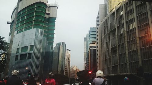 People on street amidst buildings in city against sky