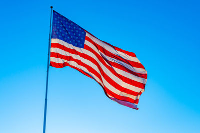 Low angle view of flag against blue sky