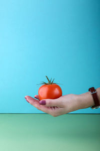 Midsection of man holding apple against blue background