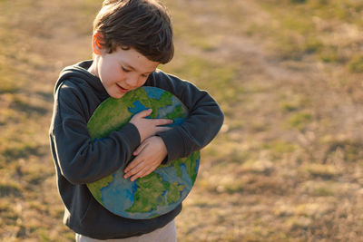 Boy embracing globe against sky