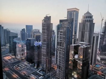 Modern buildings in city against sky during sunset