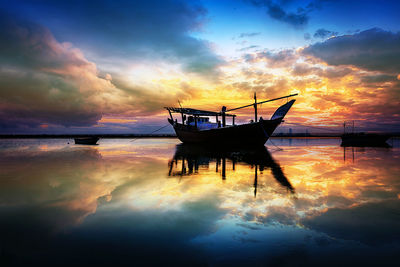 Fishing boat in sea against sky during sunset