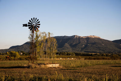 Windmill on field against clear sky