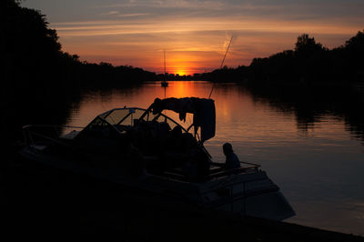 Silhouette boat in lake against sky during sunset