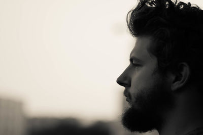 Close-up of thoughtful bearded man against sky