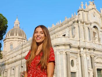 Portrait of a smiling young woman against building