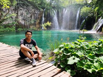 Young man sitting by waterfall