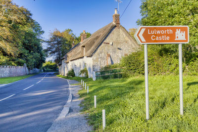 Road sign by building against sky