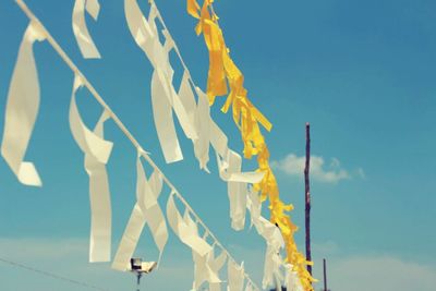 Low angle view of clothes hanging against blue sky