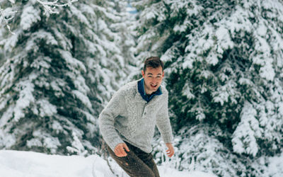 Young man standing in snow covered forest
