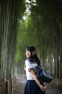 Rear view portrait of young woman in bamboo groove