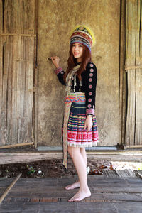 Portrait of a smiling young woman standing against wall