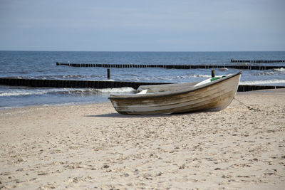 Boat moored on beach against sky