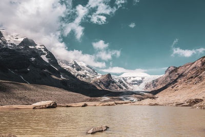 Scenic view of lake by snowcapped mountains against sky