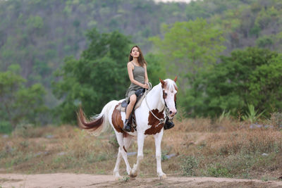 Full length of young woman riding horse