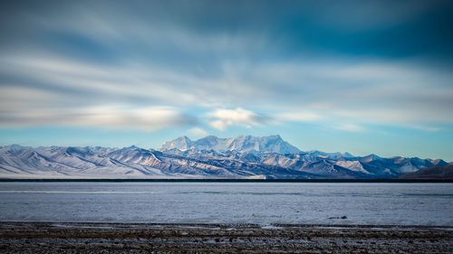 Scenic view of lake by mountains against sky