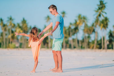Full length of father and daughter standing on beach