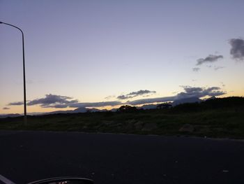 Road by landscape against sky during sunset