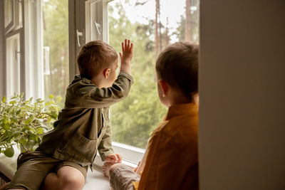 Children sitting on windowsill and waiting for someone comming. two brothers, friends. 