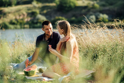 Young couple in love on summer picnic with watermelon. loving couple sitting by the river, talking