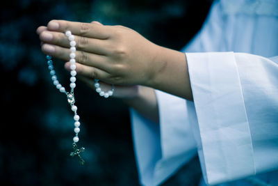 Midsection of person holding rosary beads