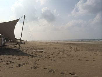 Scenic view of beach against cloudy sky