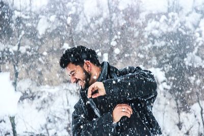 Young man standing on snow covered trees