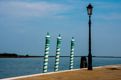 Street light by sea against blue sky