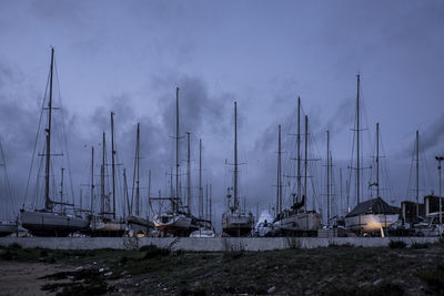 Sailboats in river against cloudy sky at dusk