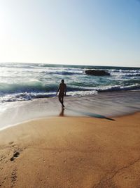 Rear view of woman on beach against clear sky