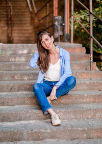 Portrait of smiling young woman sitting on staircase