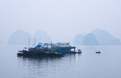 Fishing boats in sea against clear sky