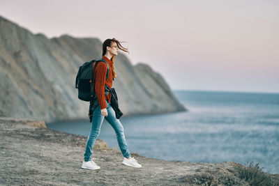 Full length of woman standing on beach against sea and sky