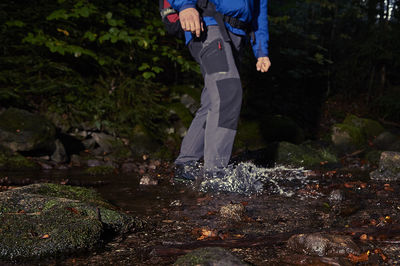 Low section of man standing in stream