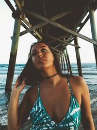 Young woman below pier at beach