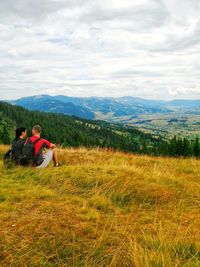 People sitting on mountain against sky