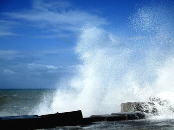 Waves splashing in sea against sky