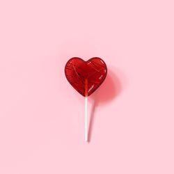 Close-up of heart shape candy on pink background