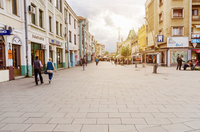 People walking on footpath amidst buildings in city