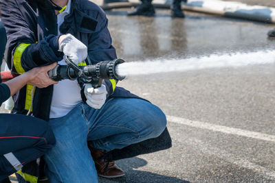 Firefighter shows trainee how to extinguish a fire with water