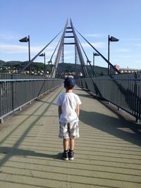 Rear view of boy standing on bridge