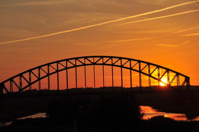 Silhouette railway bridge against sky during sunset